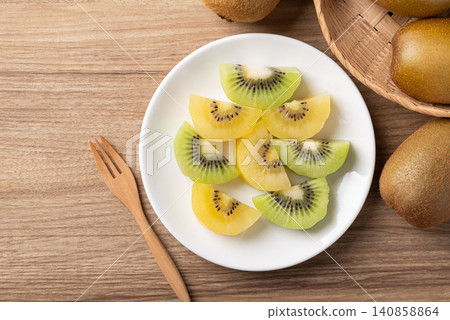 Sliced gold and green kiwi fruit on a white plate ready to eating. Healthy fruit. Table top view Sliced gold and green kiwi fruit on a white plate ready to eating. Healthy fruit. Table top view 140858864