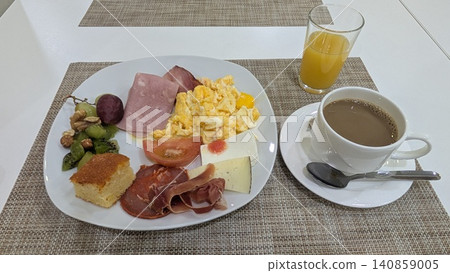 Breakfast with scrambled eggs, fruits with nuts,  various hams and cheese, and beverages 140859005