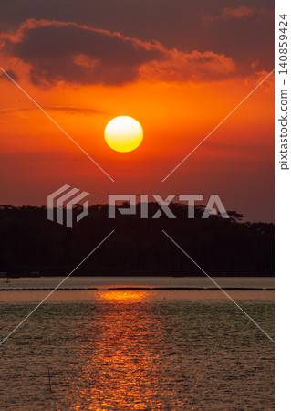 Beautiful golden sunset over the river with a small boat and sun reflection on the water. Beautiful golden sunset over the river with a small boat and sun reflection on the water. 140859424