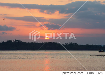 Beautiful golden sunset over the river with a small boat and sun reflection on the water. Beautiful golden sunset over the river with a small boat and sun reflection on the water. 140859428
