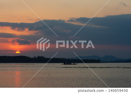 Beautiful golden sunset over the river with a small boat and sun reflection on the water. Beautiful golden sunset over the river with a small boat and sun reflection on the water. 140859430