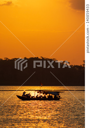 Beautiful golden sunset over the river with a small boat and sun reflection on the water. Beautiful golden sunset over the river with a small boat and sun reflection on the water. 140859433
