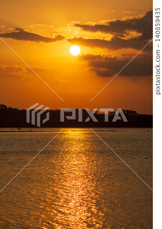 Beautiful golden sunset over the river with a small boat and sun reflection on the water. Beautiful golden sunset over the river with a small boat and sun reflection on the water. 140859435