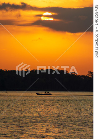 Beautiful golden sunset over the river with a small boat and sun reflection on the water. Beautiful golden sunset over the river with a small boat and sun reflection on the water. 140859439