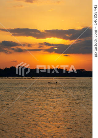 Beautiful golden sunset over the river with a small boat and sun reflection on the water. Beautiful golden sunset over the river with a small boat and sun reflection on the water. 140859442