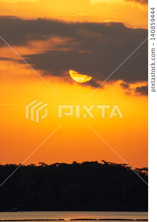 Beautiful golden sunset over the river with a small boat and sun reflection on the water. Beautiful golden sunset over the river with a small boat and sun reflection on the water. 140859444