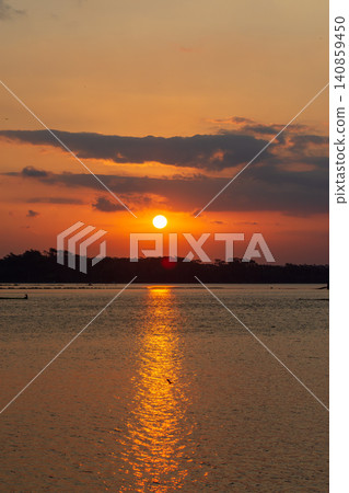 Beautiful golden sunset over the river with a small boat and sun reflection on the water. Beautiful golden sunset over the river with a small boat and sun reflection on the water. 140859450