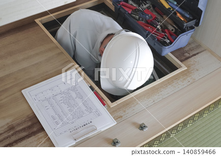 A worker inspects the area under the floor through an underfloor inspection hatch. A worker inspects the area under the floor through an underfloor inspection hatch. 140859466