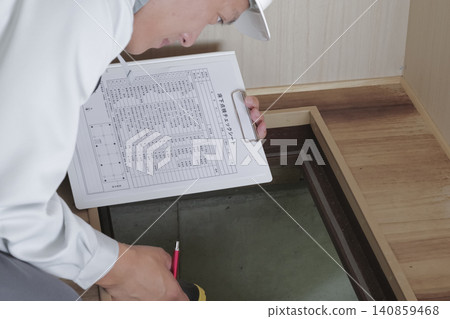 A worker inspects the area under the floor through an underfloor inspection hatch. A worker inspects the area under the floor through an underfloor inspection hatch. 140859468