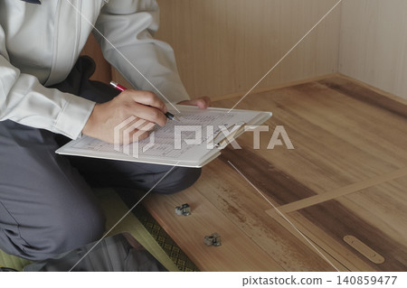 一名工人透過地板下的檢查艙口檢查地板下的區域。 一名工人透過地板下的檢查艙口檢查地板下的區域。 140859477