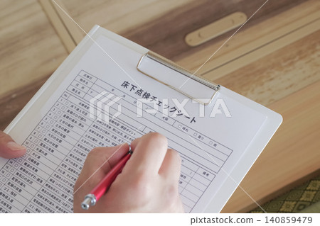 A worker inspects the area under the floor through an underfloor inspection hatch. A worker inspects the area under the floor through an underfloor inspection hatch. 140859479