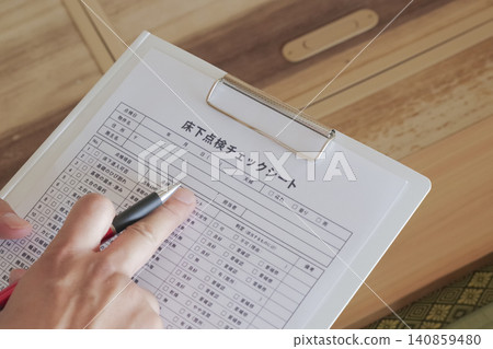 A worker inspects the area under the floor through an underfloor inspection hatch. 140859480