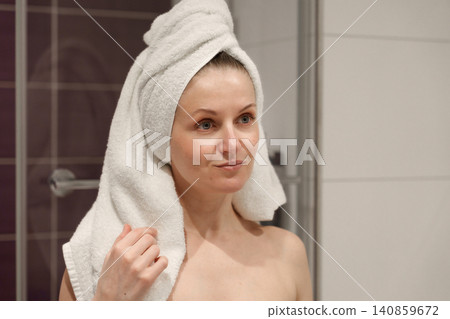 Woman with towel on head after shower in bathroom Woman with towel on head after shower in bathroom 140859672