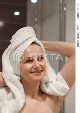 Smiling woman with towel on head after shower Smiling woman with towel on head after shower 140859685