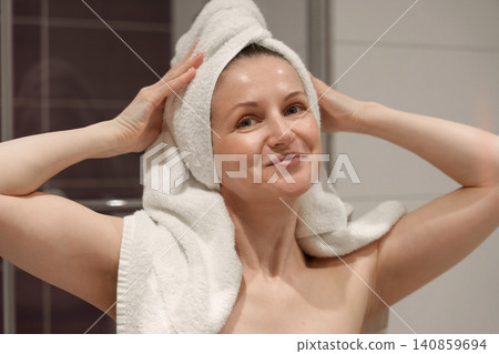 Smiling woman with towel on head after shower Smiling woman with towel on head after shower 140859694