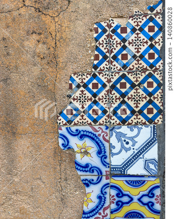 Vintage mismatched Portuguese tiles on cracked stucco 140860028