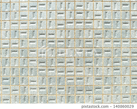 A flat front view of a geometric wall pattern featuring small light blue textured ceramic tiles arranged in a uniform grid with visible mortar lines 140860029