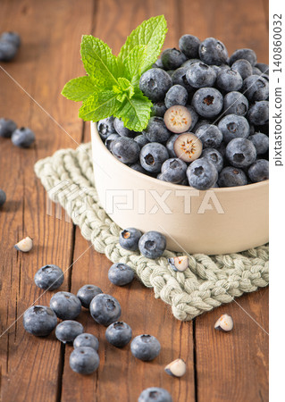 Fresh blueberries and green mint in a bowl on a wooden table make a vibrant, healthy display for food lovers 140860032