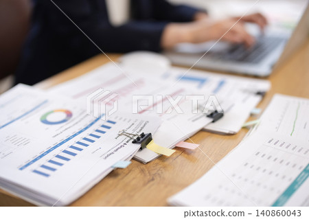 A close-up of documents on the desk of a businesswoman working on her computer. A close-up of documents on the desk of a businesswoman working on her computer. 140860043