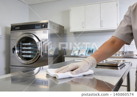 Sterilization technician cleans medical equipment in a sterile laboratory environment Sterilization technician cleans medical equipment in a sterile laboratory environment 140860574