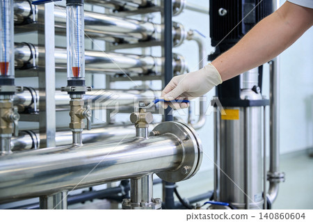 Operator in sterile glove adjusts valve on industrial stainless steel pipe system Operator in sterile glove adjusts valve on industrial stainless steel pipe system 140860604