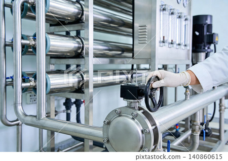 Scientist adjusting valve on industrial water purification system with stainless steel pipes 140860615