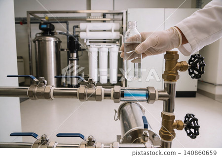 Scientist examines purified water sample from advanced filtration system 140860659