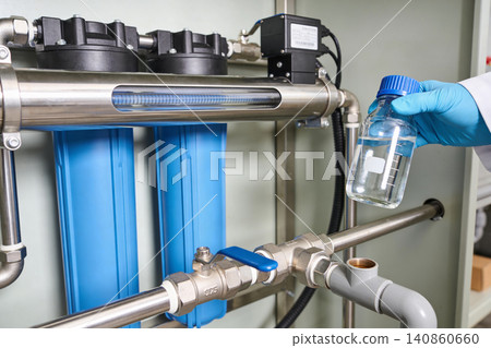Scientist examines purified water sample from advanced filtration system Scientist examines purified water sample from advanced filtration system 140860660