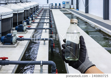 Aquaculture facility with tanks, pumps, and water channels, water sample in hand Aquaculture facility with tanks, pumps, and water channels, water sample in hand 140860725