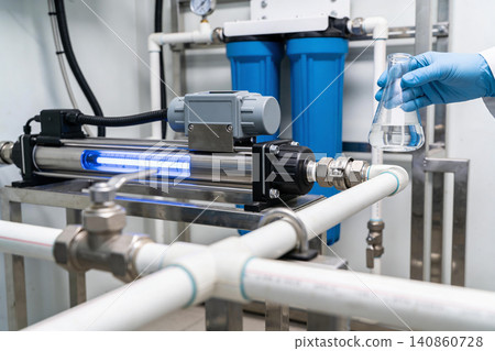 Scientist examines UV water purification system with blue filters and flask Scientist examines UV water purification system with blue filters and flask 140860728