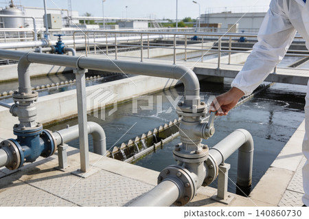 Worker in protective suit adjusts valve at wastewater treatment plant Worker in protective suit adjusts valve at wastewater treatment plant 140860730