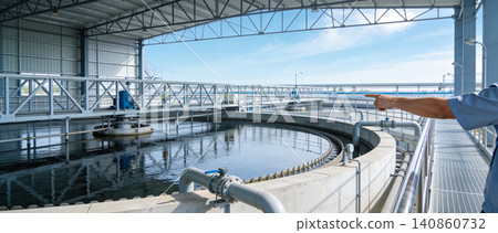Wastewater treatment plant with a worker pointing towards the circular clarifier Wastewater treatment plant with a worker pointing towards the circular clarifier 140860732
