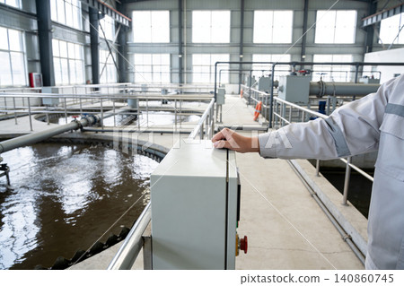 Worker overseeing operations at a modern wastewater treatment plant facility 140860745