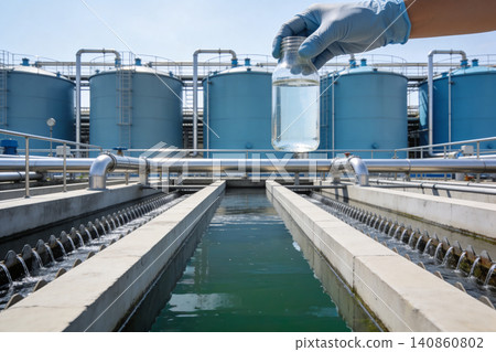 Water treatment plant with hand holding sample of purified water in a glass jar Water treatment plant with hand holding sample of purified water in a glass jar 140860802