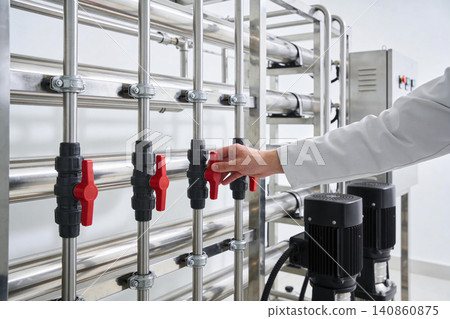 Industrial technician adjusts valves on a complex water purification system Industrial technician adjusts valves on a complex water purification system 140860875