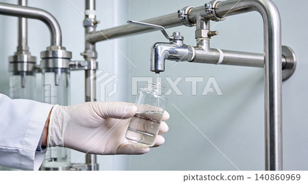 Scientist collecting liquid sample from laboratory equipment for analysis Scientist collecting liquid sample from laboratory equipment for analysis 140860969