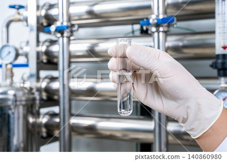 Scientist examines liquid sample in test tube at industrial water purification plant 140860980