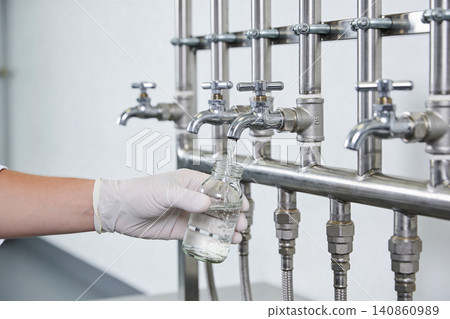 Scientist collecting liquid sample from laboratory faucet into glass bottle Scientist collecting liquid sample from laboratory faucet into glass bottle 140860989