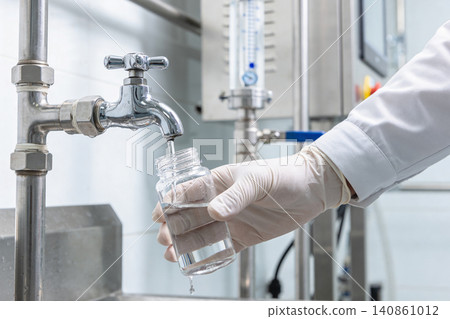 Scientist in lab coat and gloves collecting water sample from faucet for analysis Scientist in lab coat and gloves collecting water sample from faucet for analysis 140861012