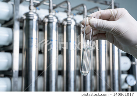 Scientist examines liquid sample in test tube at water purification plant Scientist examines liquid sample in test tube at water purification plant 140861017