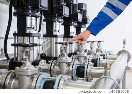 Technician operating valve on industrial pump system with multiple units Technician operating valve on industrial pump system with multiple units 140861028