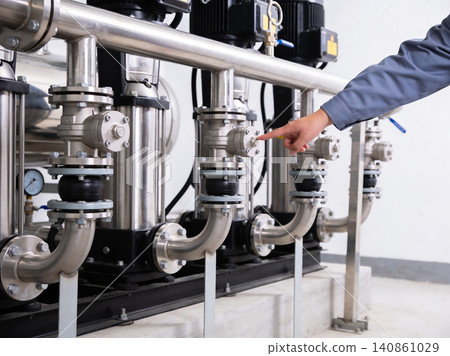 Engineer's hand adjusting valve on industrial pump system for optimal performance 140861029