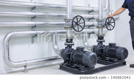 Industrial pumps and pipes with a technician adjusting a valve in a clean facility Industrial pumps and pipes with a technician adjusting a valve in a clean facility 140861041