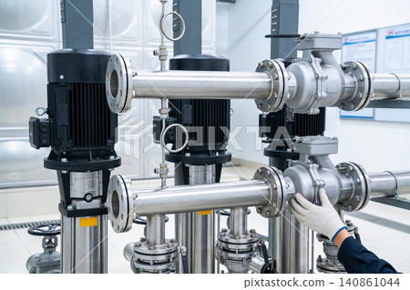 Industrial pumps and piping system with technician's hand in white glove inspecting valves Industrial pumps and piping system with technician's hand in white glove inspecting valves 140861044