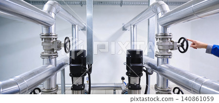 Industrial plumbing system with pumps and valves, technician adjusting control 140861059