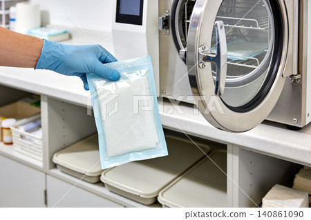 Healthcare professional places sterile packaged medical instruments into an autoclave 140861090