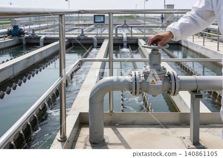 Operator adjusts valve at water treatment plant with cascading water channels Operator adjusts valve at water treatment plant with cascading water channels 140861105
