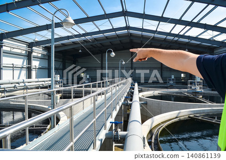 Industrial water treatment plant with circular clarifier tanks and pointing hand 140861139
