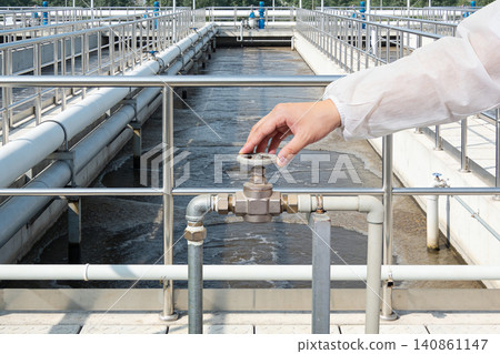 Operator adjusts valve controlling water flow in industrial treatment plant Operator adjusts valve controlling water flow in industrial treatment plant 140861147