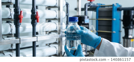 Scientist holding purified water sample in laboratory with filtration system 140861157